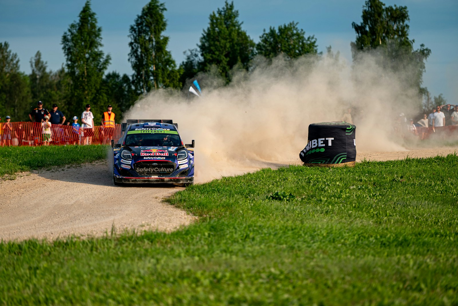 A rally car throwing up dust on a gravel stage