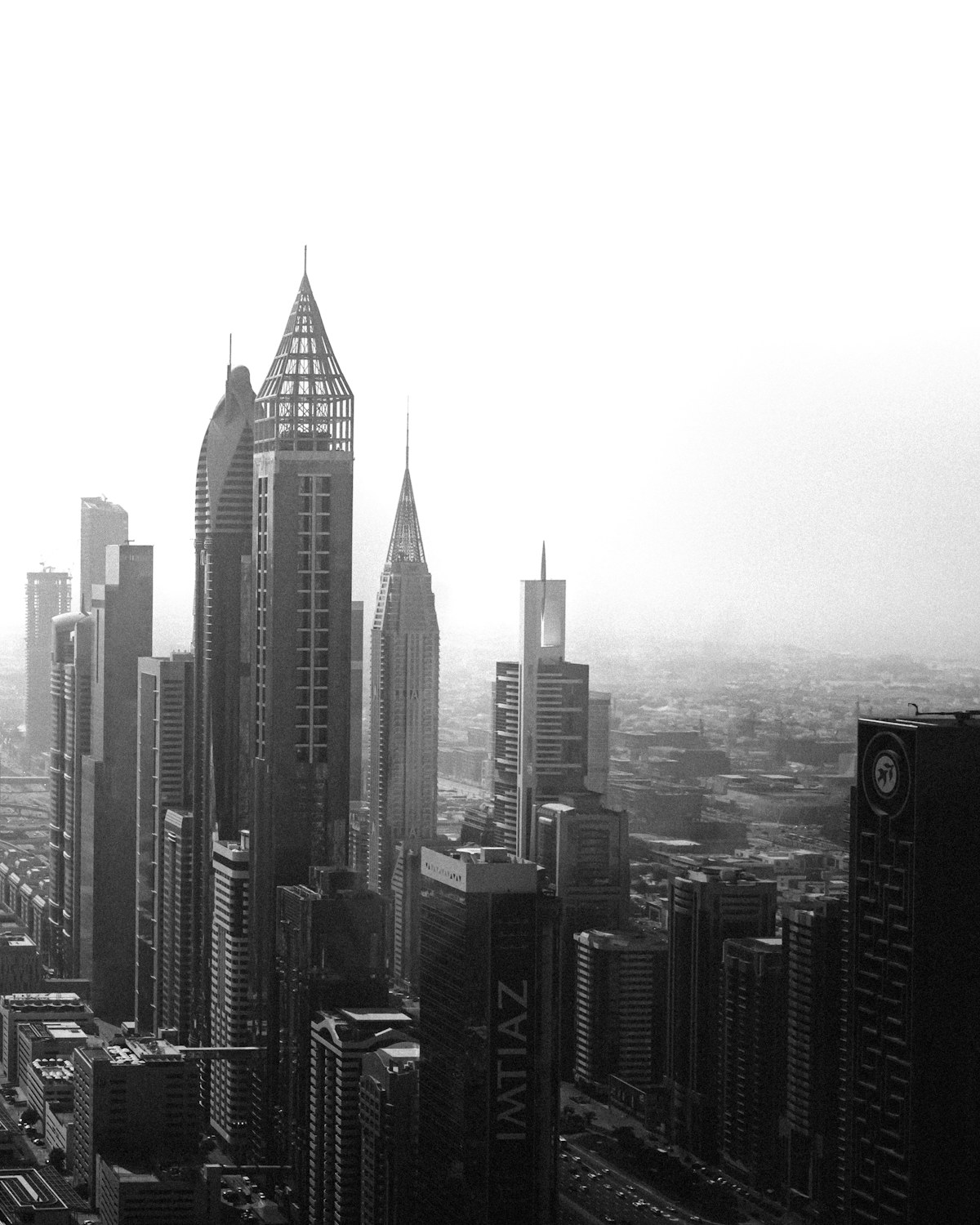 A global city skyline of towers emerging through haze